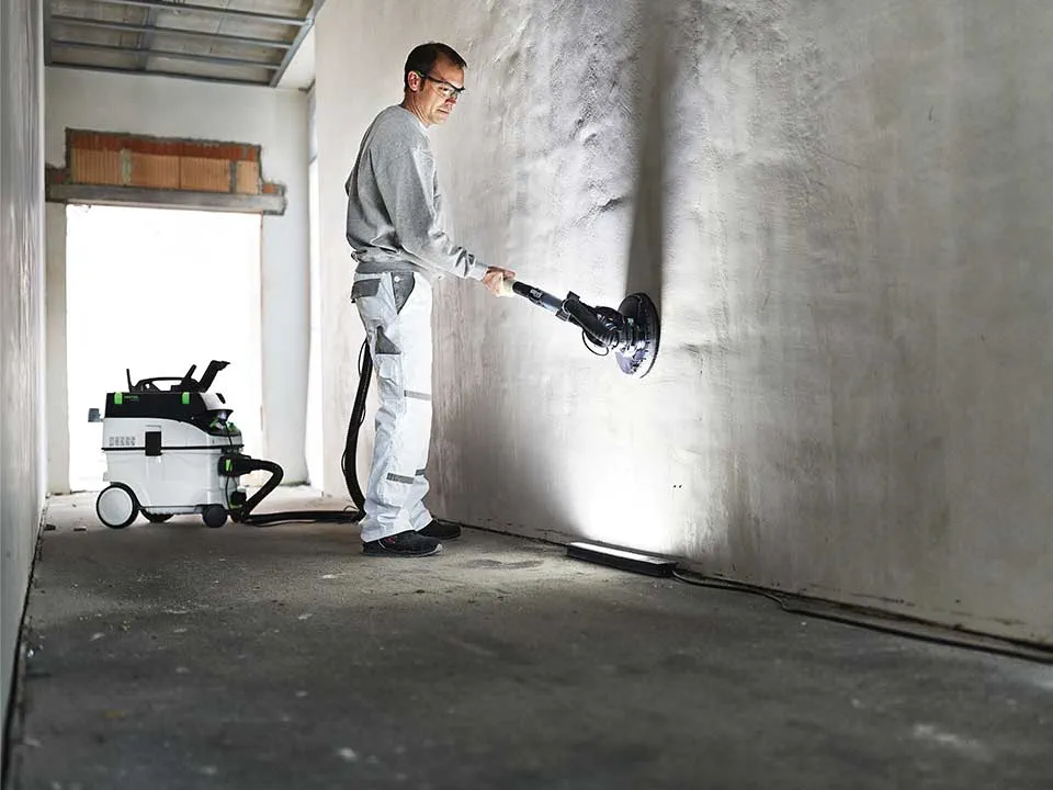 Käsitööline valgustab seina abil maalri pinna kontrollvalgusti ja lihvib selle maha